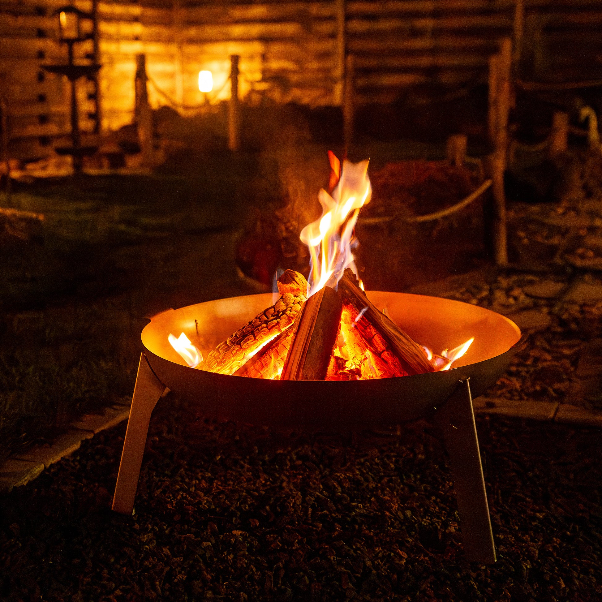 In der Feuerschale 3Pod Edelstahl brennt ein schönes Lagerfeuer im abendlichen Ambiente.