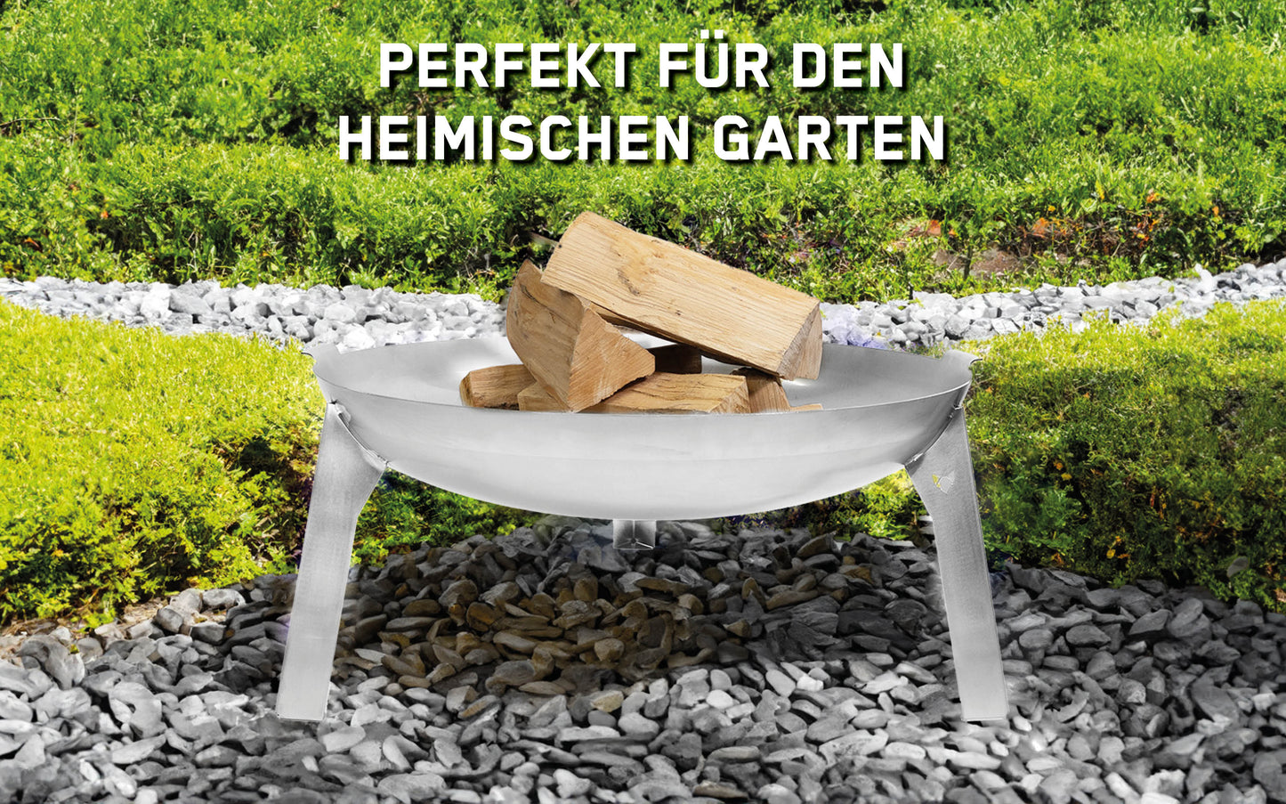 Feuerschale 3Pod Edelstahl steht auf Steinen in einem Garten und ist mit Holz befüllt. Im Hintergrund sind kleine Hecken und Grünpflanzen zu sehen. Über der Feuerschale steht ein Schriftzug: Perfekt für den heimischen Garten.