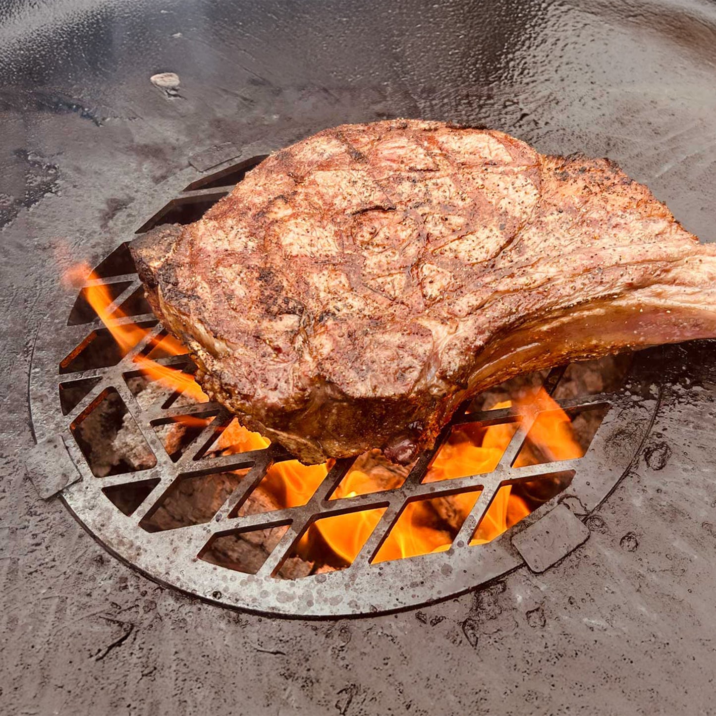 Edelstahl Grilleinsatz für die FENNEK Feuerschale Allround aus Edelstahl im Einsatz. Das saftige Steak liegt direkt auf dem Grilleinsatz, damit es direktes Feuer abbekommt.