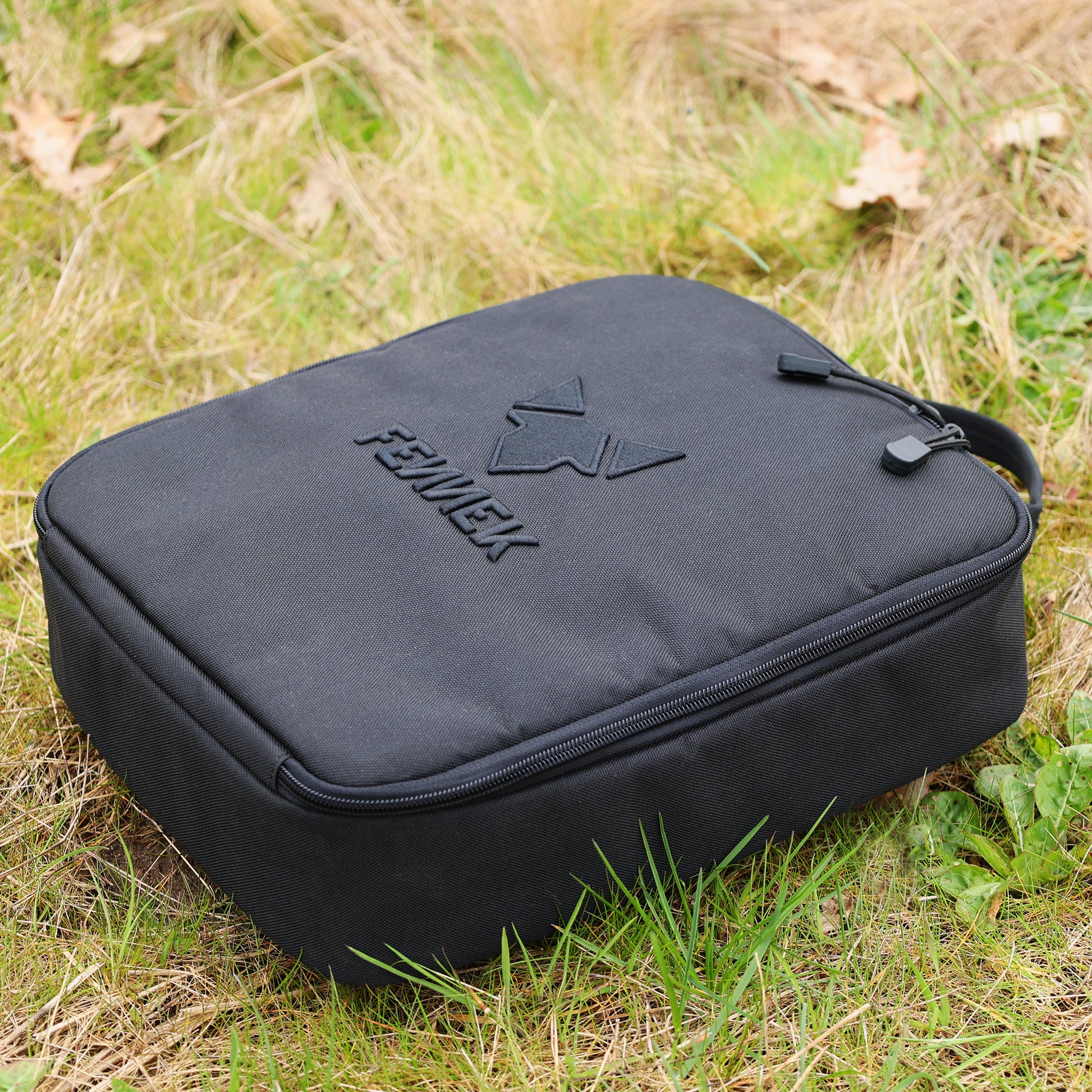 Die FENNEK Kühltasche liegt auf einer Wiese.