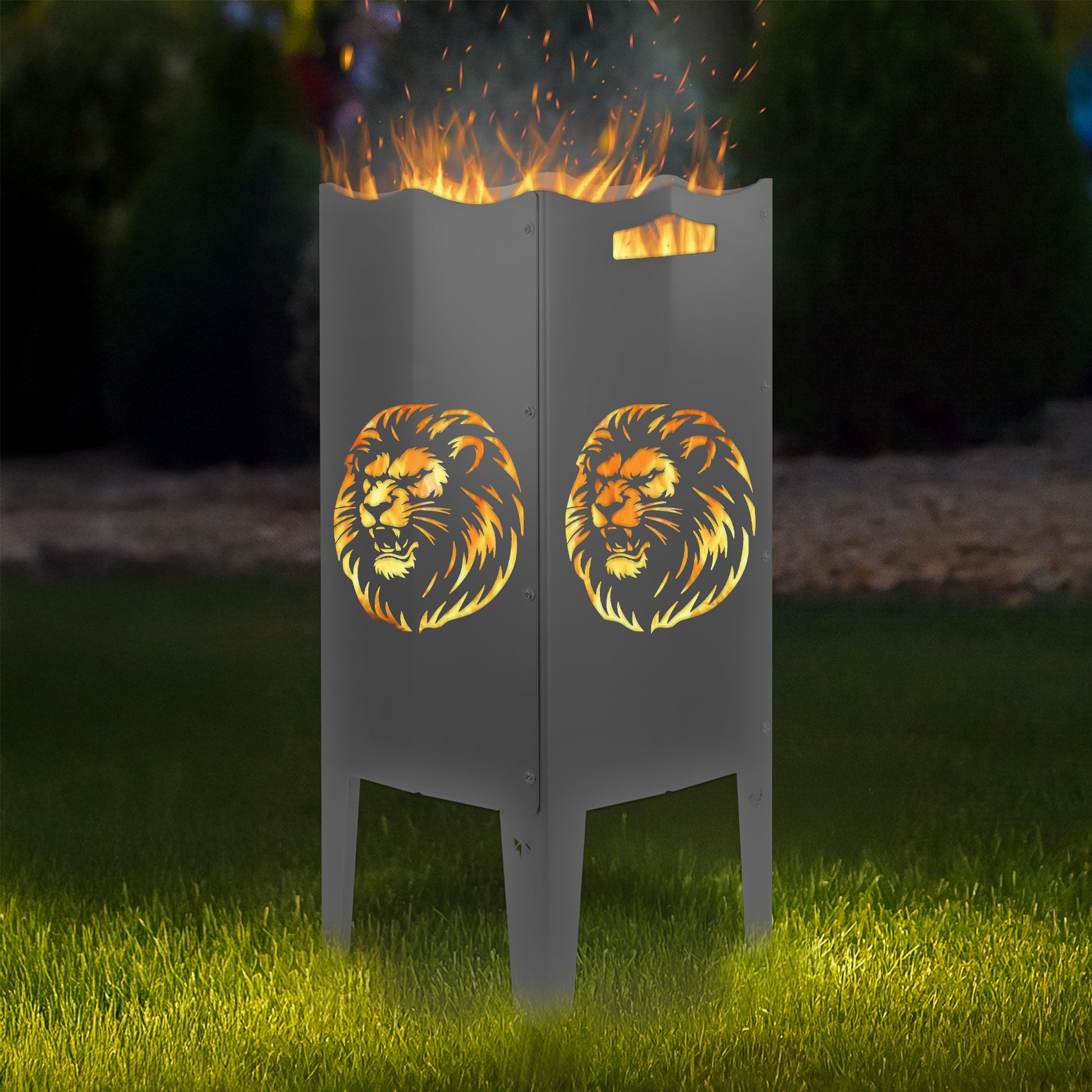 FENNEK Feuersäule Stahl mit dem Motiv Löwe - in der Feuersäule brennt ein Feuer, man sieht das Motiv sehr schön leuchten in der Abenddämmerung in einem Garten. Die Feuersäule steht auf Gras.