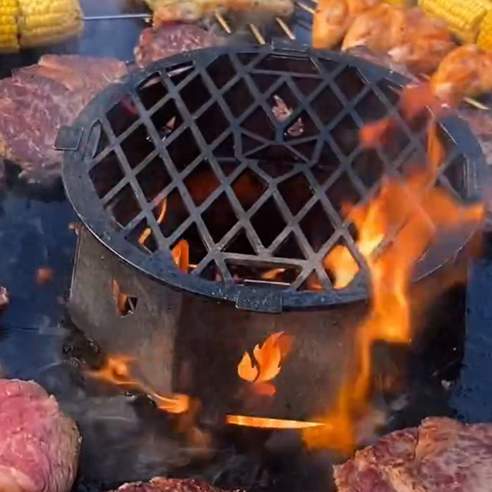 Die FENNEK Feuerschale mit Krone in Action. Ringsrum grillt Fleisch und Mais auf der Feuerplatte.