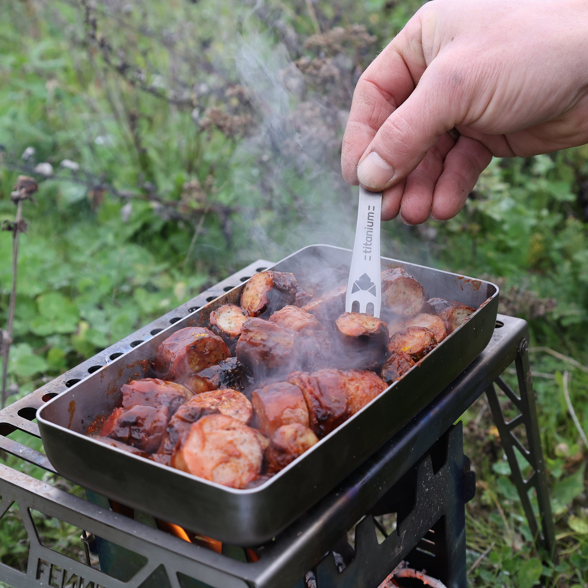 Pieker Pommesgabel mit Titanium-Schriftzug graviert spießt im Einsatz ein Stück Currywurst auf