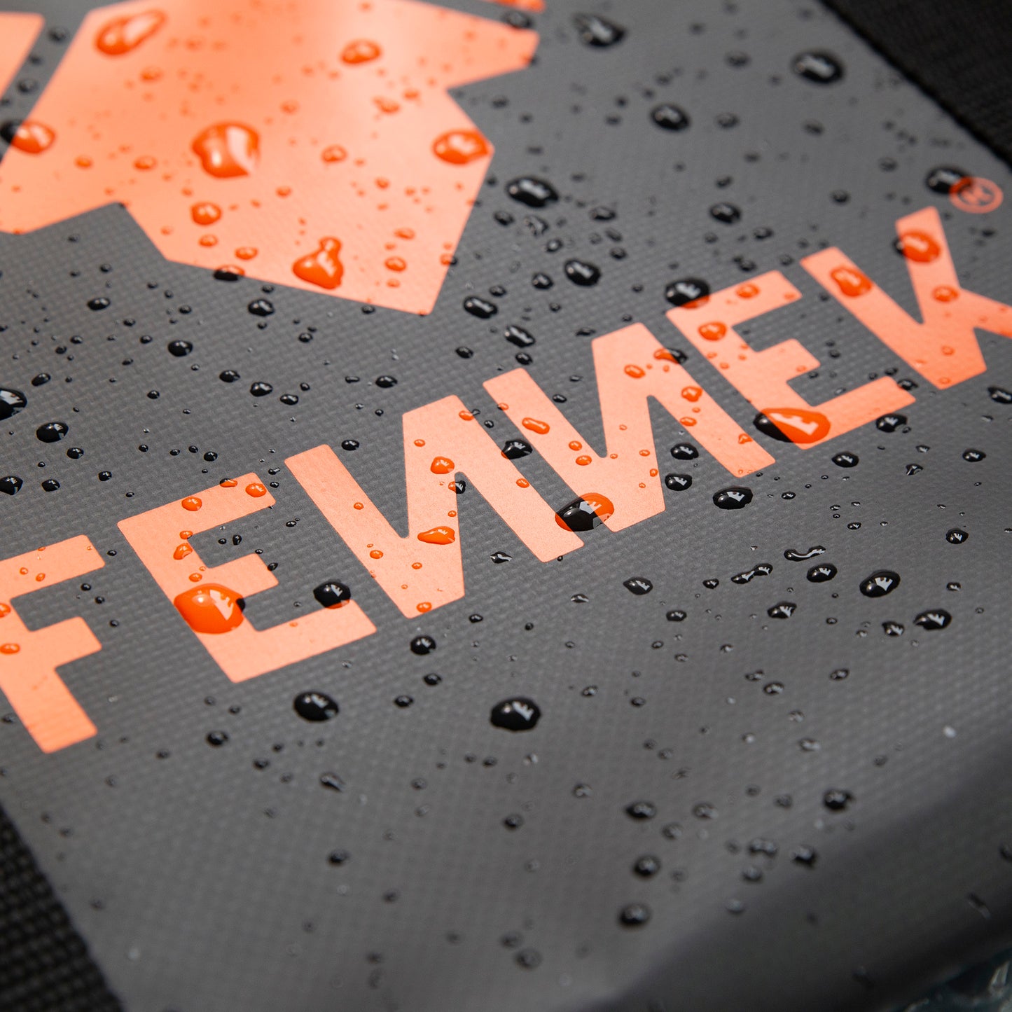 Detailbild der FENNEK Tasche, zu sehen sind das aufgedruckte FENNEK Logo und abperlende Wassertropfen.
