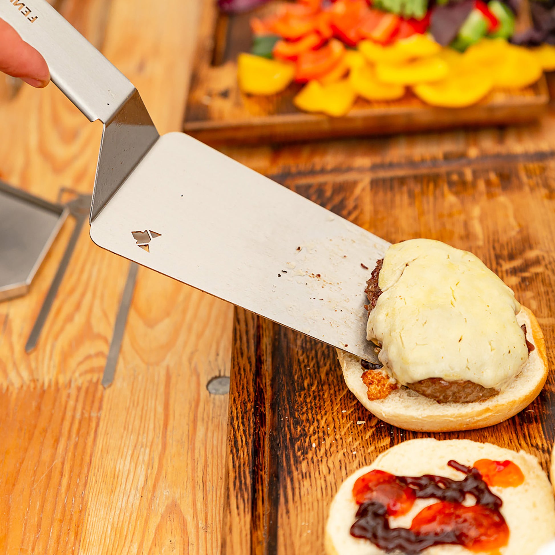 BBQ-Wender legt mit Käse überbackene Burgerpatties auf Brötchen.