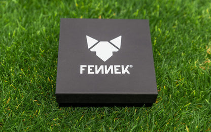 Edle schwarze Geschenkverpackung mit hellgrauem FENNEK Logo-Aufdruck auf der Oberseite, liegt auf grünem Rasen