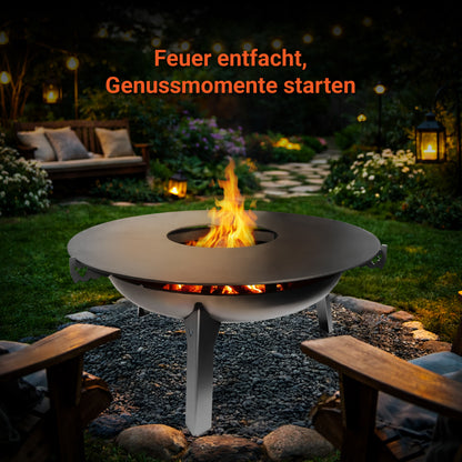 Die FENNEK Auflageleiste für Feuerplatten Ø 96 liegt auf der FENNEK Feuerschale 3Pod mit der passenden FENNEK Feuerplatte Ø 96. Die Feuerschale steht auf einem Kiesbett in einem schönen Garten bei gemütlichem Abendlicht. Sobald das Feuer entfacht ist, können die Genussmomente starten.
