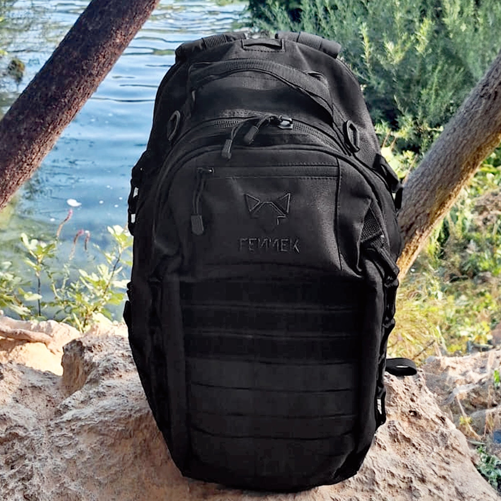 Der Backpack One2explore steht auf einem sandigen Felsen. Im Hintergrund ist ein Schwan zu sehen, der in ein Gewässer schaut. Rings um das Gewässer sind Grünpflanzen.