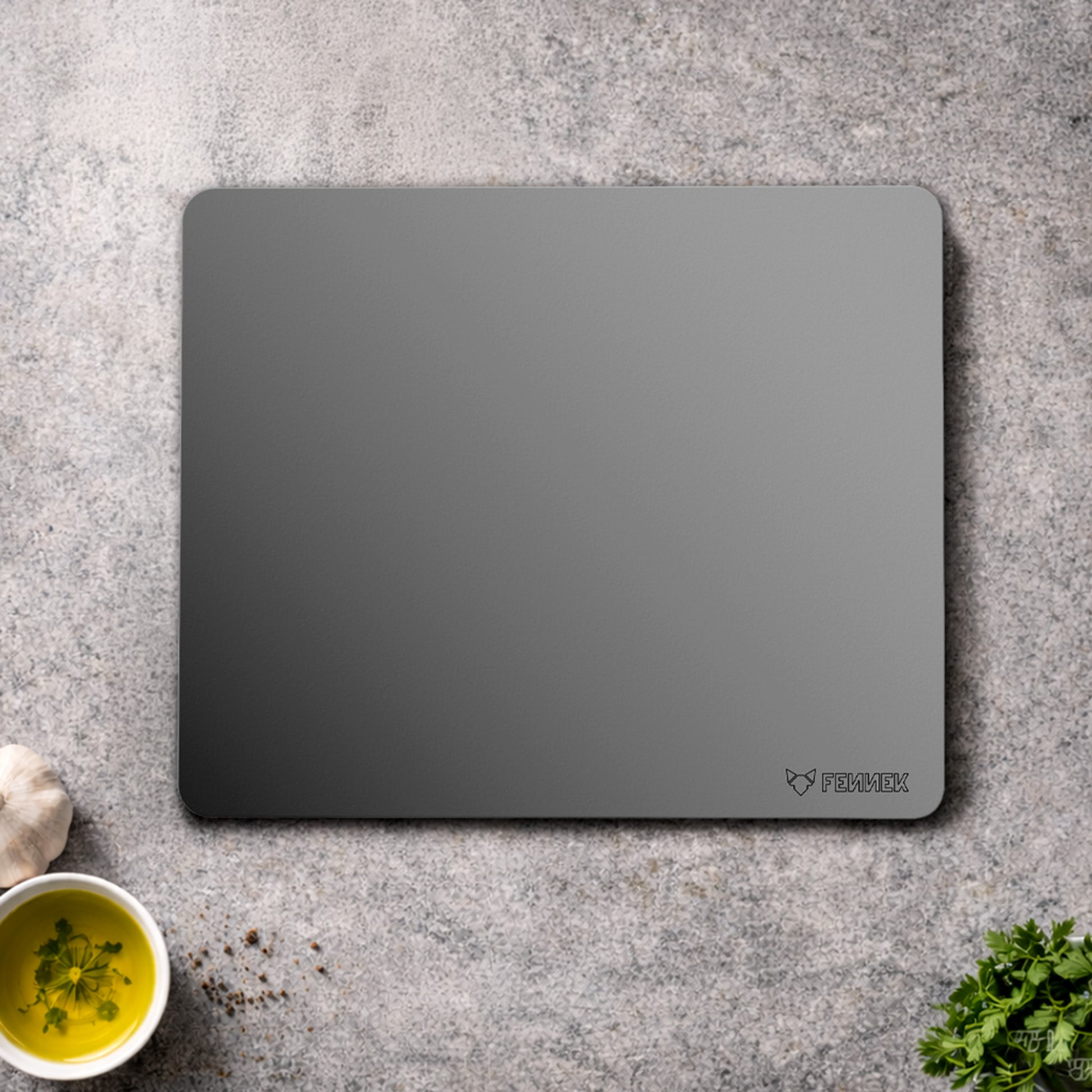 Der FENNEK Backstahl 40 x 30 cm liegt auf einer Küchenarbeitsplatte umringt von kleinen Schälchen mit Gewürzen und Kräutern.