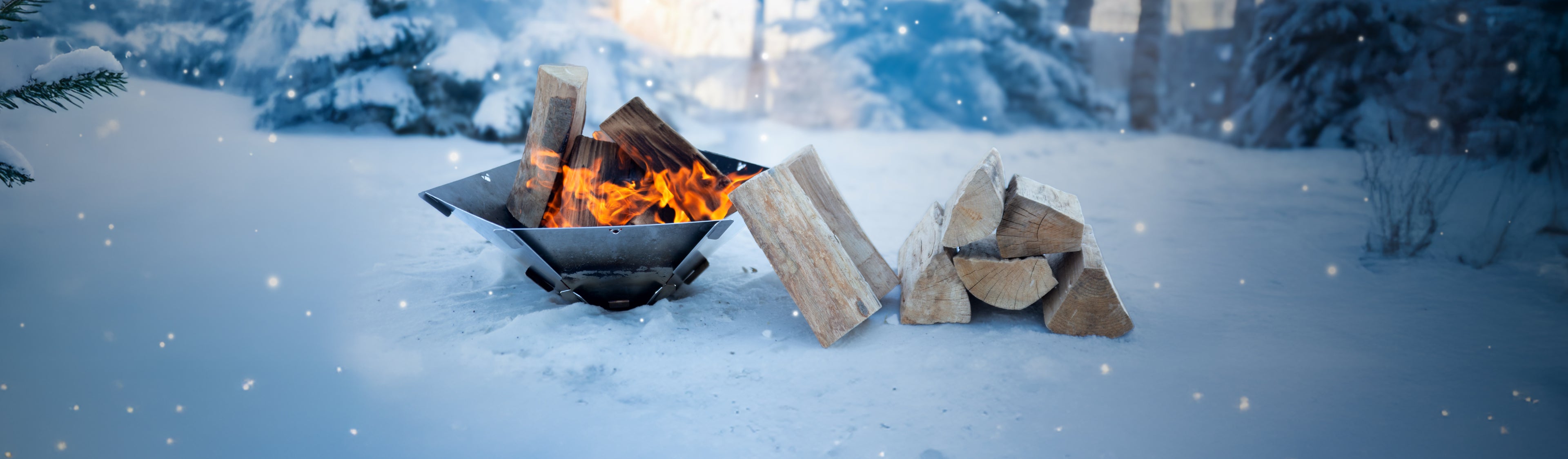 Titelbild Startseite zeigt eine winterliche Landschaft mit Feuerschale Hexagon. Darin brennt ein warmes Feuer und rechts neben der Feurschale liegt Brennholz.