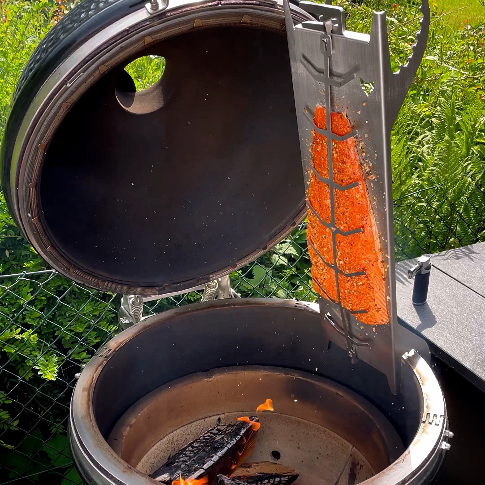 Flammlachsbrett aus Edelstahl, montiert an einem Kamado Grill.