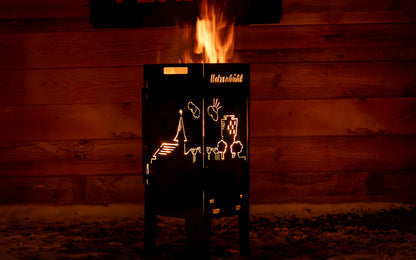 FENNEK Feuersäule Hatzenbühl Edition in Aktion mit schönem loderndem Feuer, das die auf der Feuersäule ausgelaserte Skyline von Hatzenbühl erstrahlen lässt.