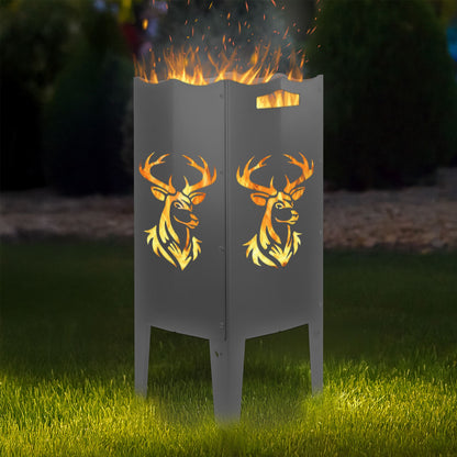 FENNEK Feuersäule Stahl mit dem Motiv Hirsch - in der Feuersäule brennt ein Feuer, man sieht das Motiv sehr schön leuchten in der Abenddämmerung in einem Garten. Die Feuersäule steht auf Gras.