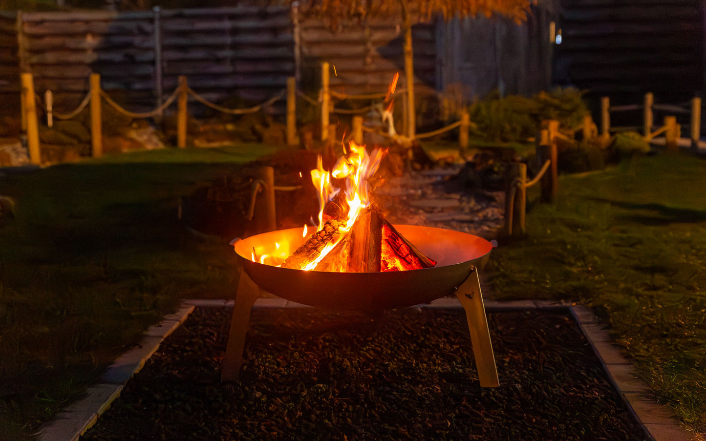 Das Lagerfeuer brennt in der Feuerschale Stahl in der abendlichen Dämmerung vor sich hin. 