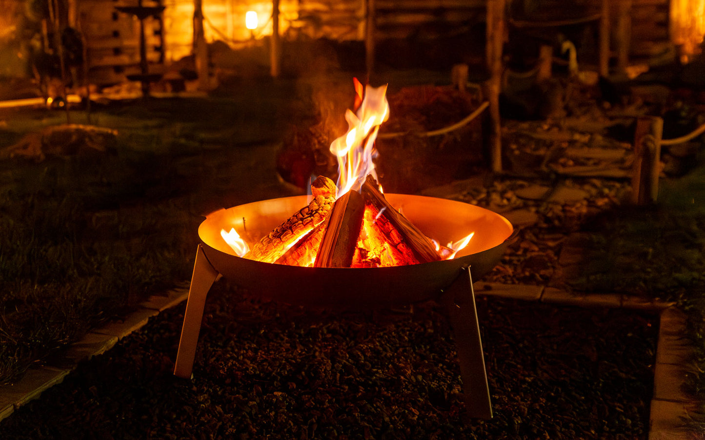 In der Feuerschale 3Pod Edelstahl brennt ein schönes Lagerfeuer im abendlichen Ambiente.