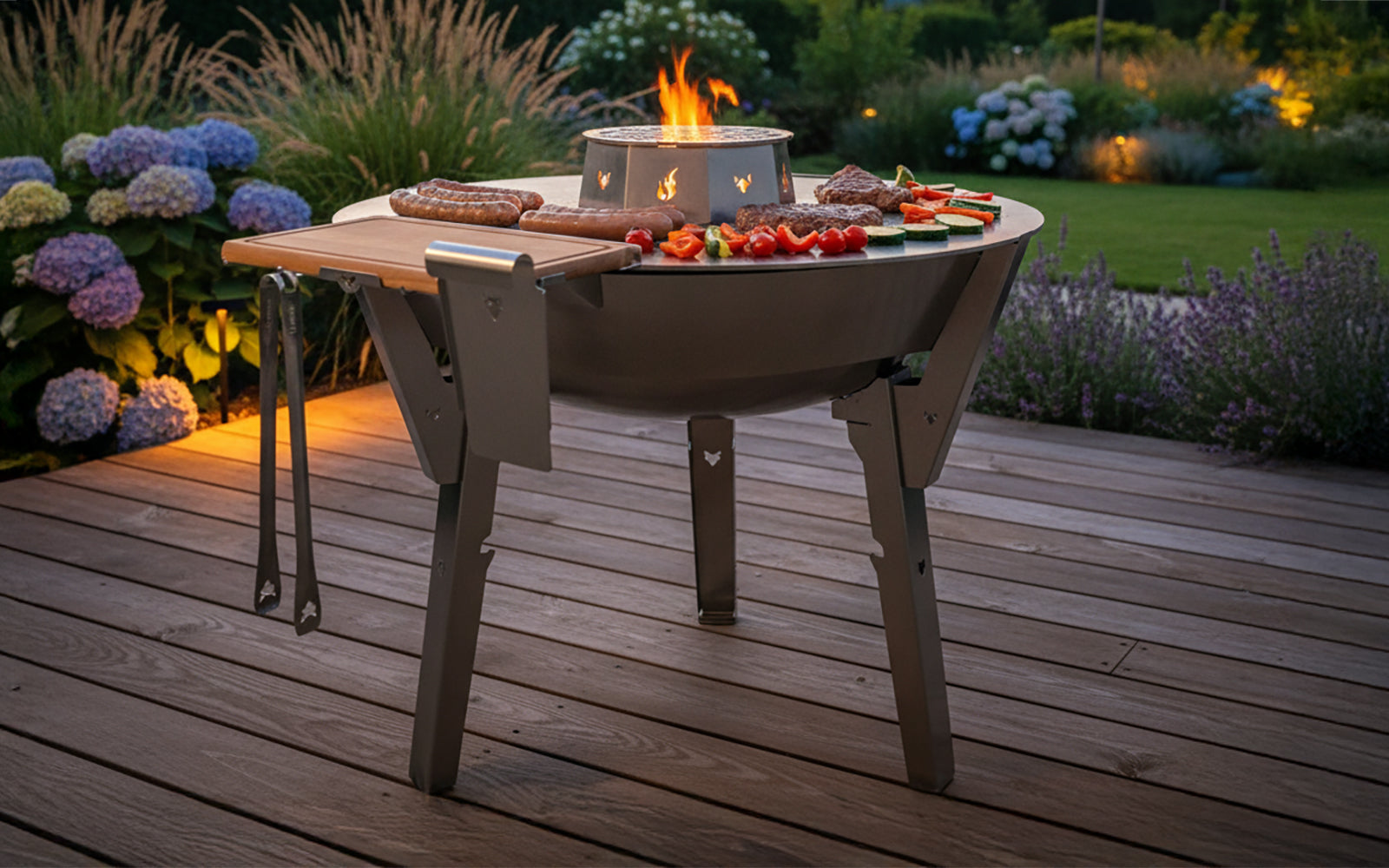 FENNEK Feuerplatte 100 cm aus massivem Feinkornstahl in Aktion. Zudem mit Zubehör wie Wok und Grillrost sowie Bretthalter. Der Feuerplattengrill steht auf einer Terrasse und es werden Würste, Steaks und Grillgemüse gegrillt. Die Feuerschale ist aus 100 % Edelstahl und wird in Deutschland hergestellt.