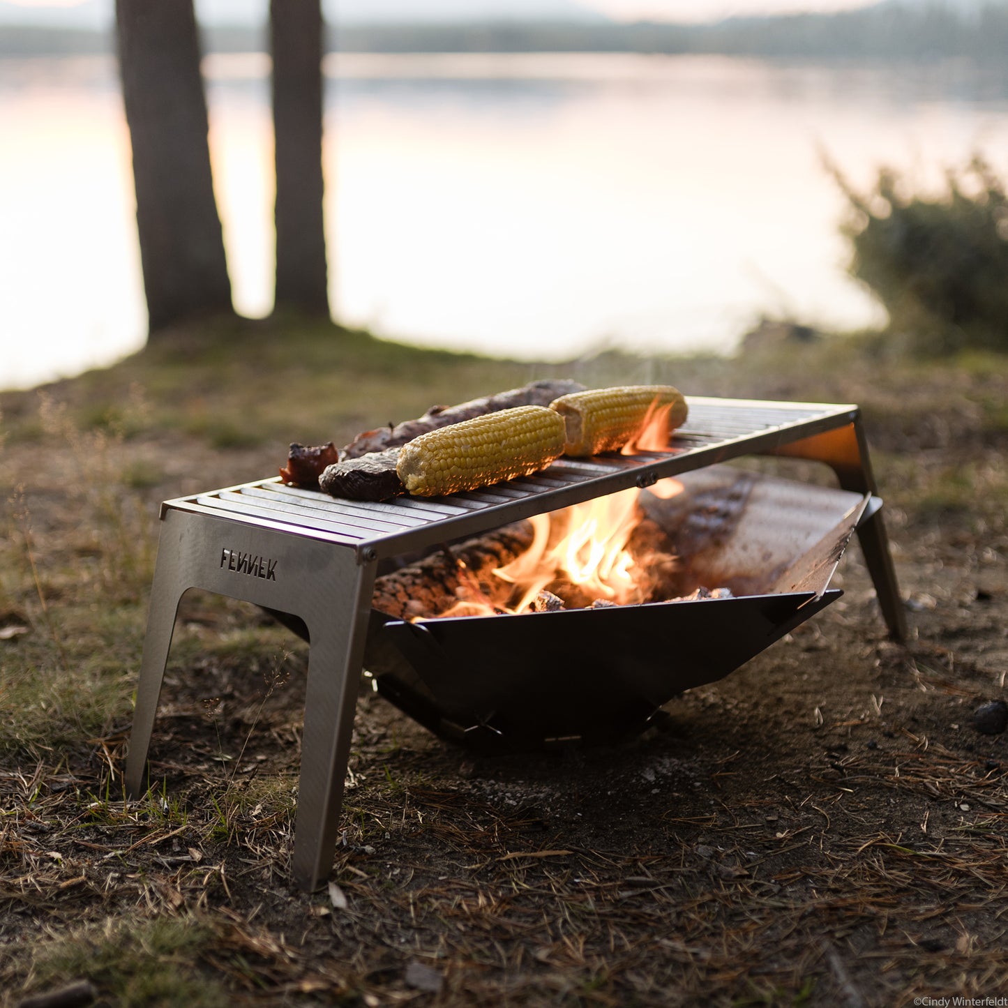 FENNEK Klapprost XL mit Feuerschale Hexagon. Auf dem Klapprost werden Mais, Schweinefilet und Steaks gegrillt. 