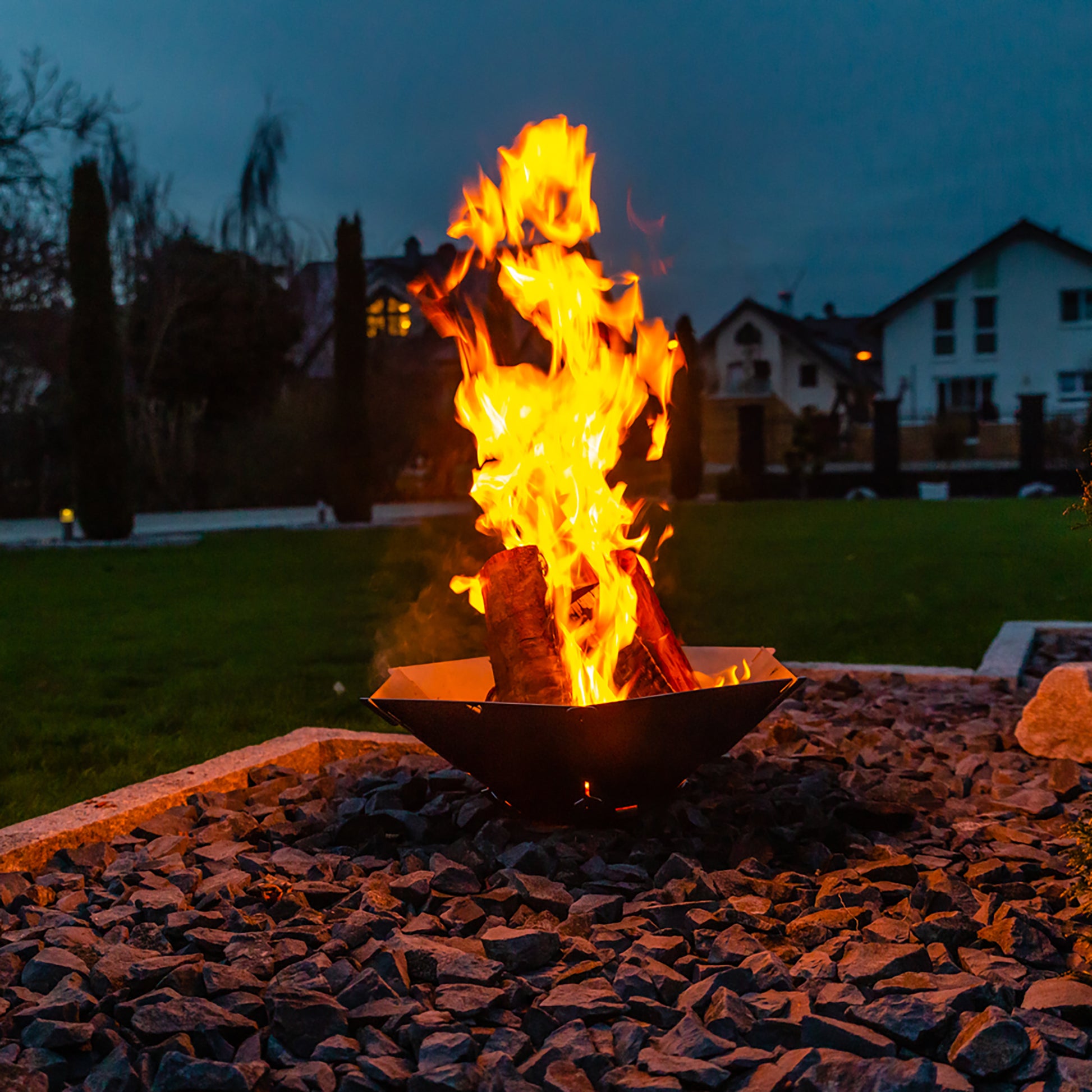 Brennendes Feuer in der Feuerschale Hexagon bei Dunkelheit im Garten..
