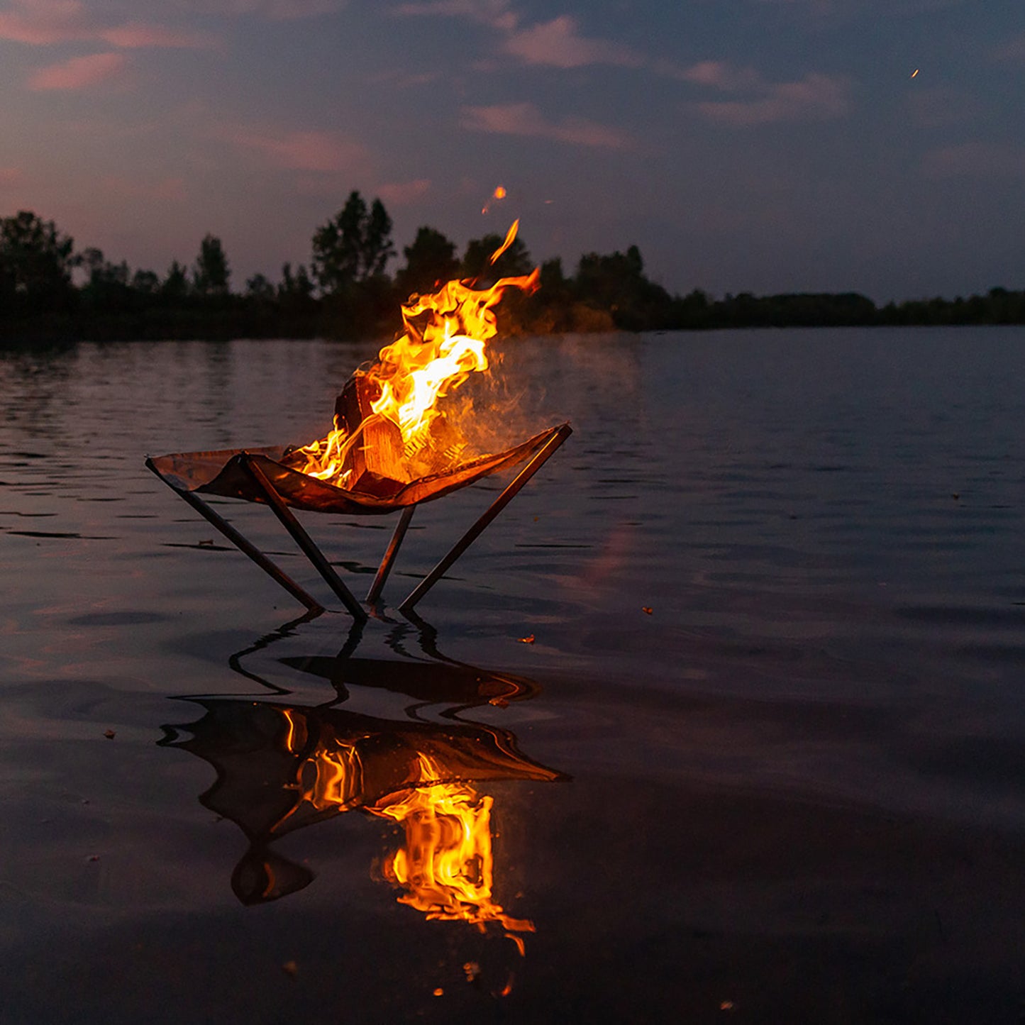 brennendes Feuer im Feuernetz das nach Sonnenuntergang im See steht und herausschaut