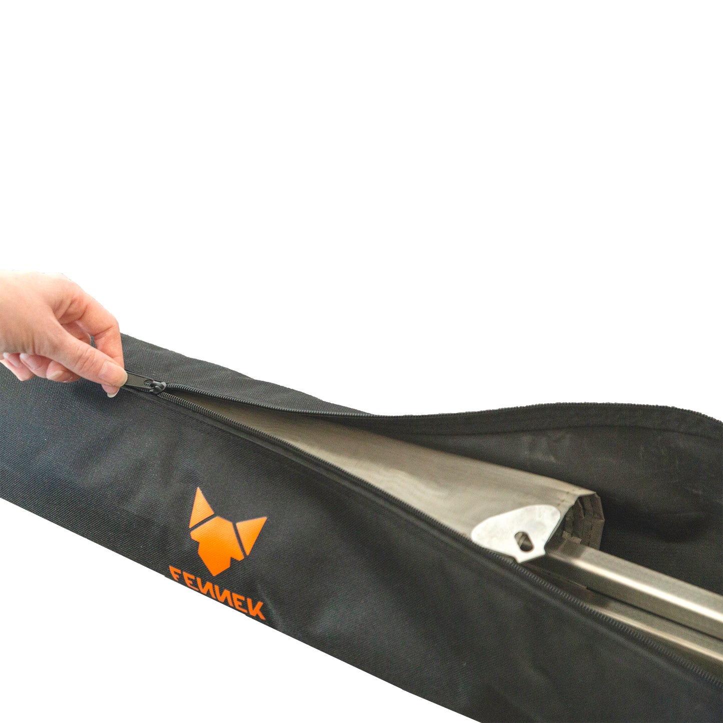Eine Hand öffnet den Reißverschluss einer schwarzen Nylon-Tasche mit FENNEK Logo-Aufdruck in orange und darin ist das verpackte Feuernetz zu sehen.