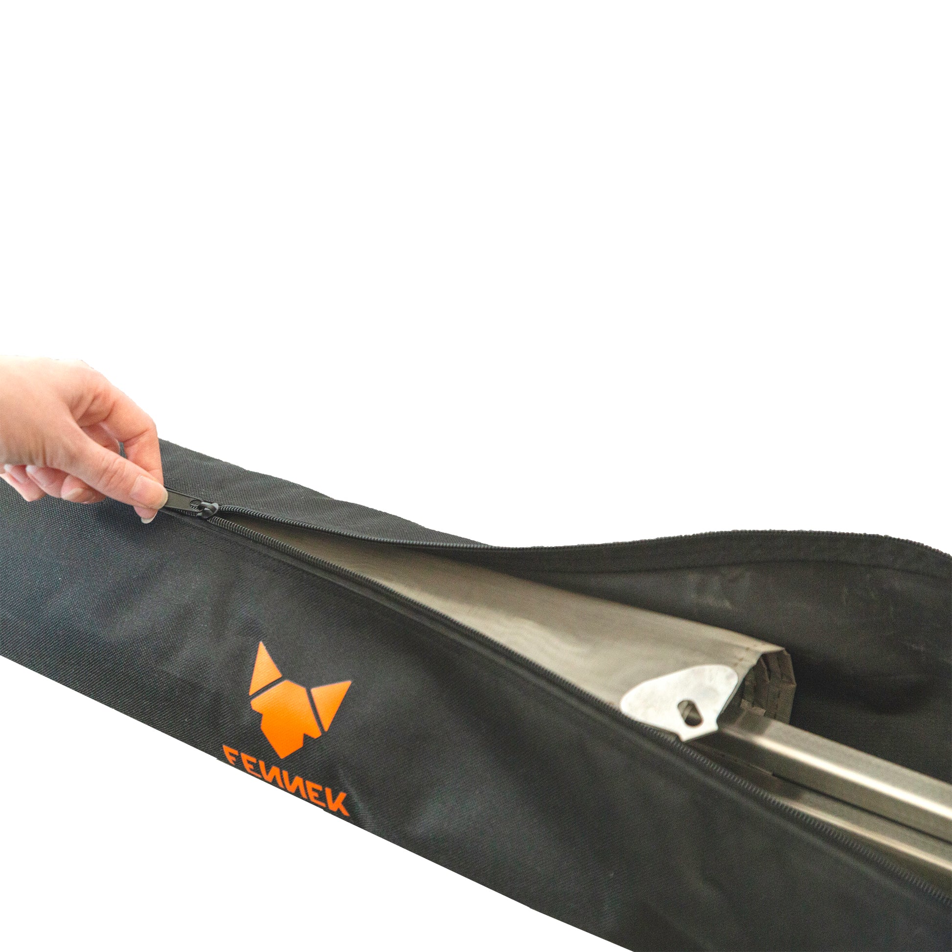 Eine Hand öffnet den Reißverschluss einer schwarzen Nylon-Tasche mit FENNEK Logo-Aufdruck in orange und darin ist das verpackte Feuernetz zu sehen.