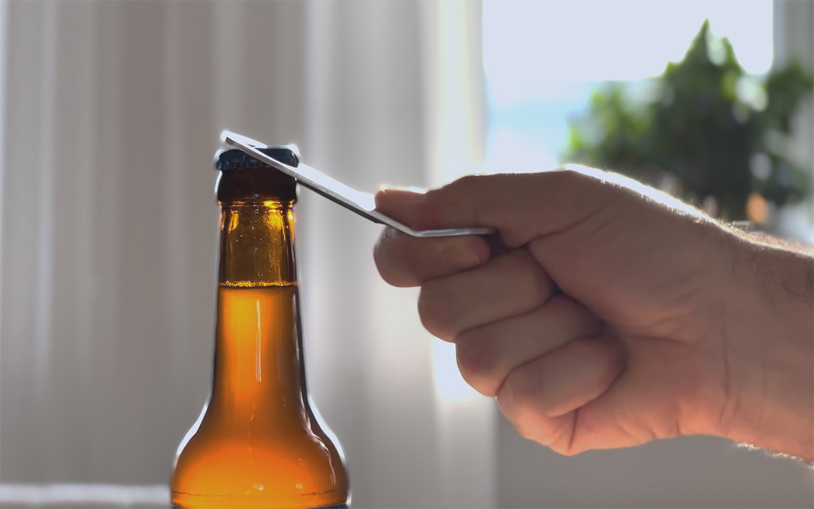 Eine Hand öffnet mit dem FENNEK Flaschenöffner Captain Cork Magnetisch Mobil eine Bierflasche.