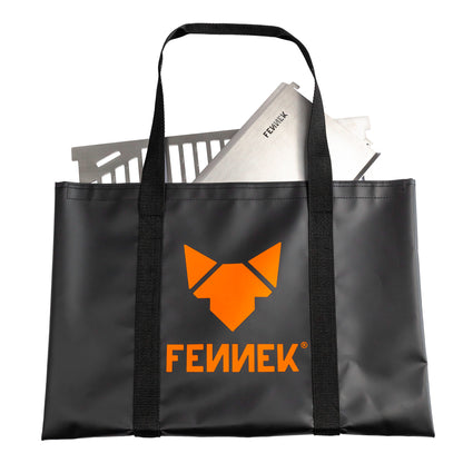 schwarze Klettverschlusstasche mit orangenem FENNEK Logo und Schriftzug. In der Tasche schaut der FENNEK 2.0 Holzkohlegrill heraus. Freistellerbild. 