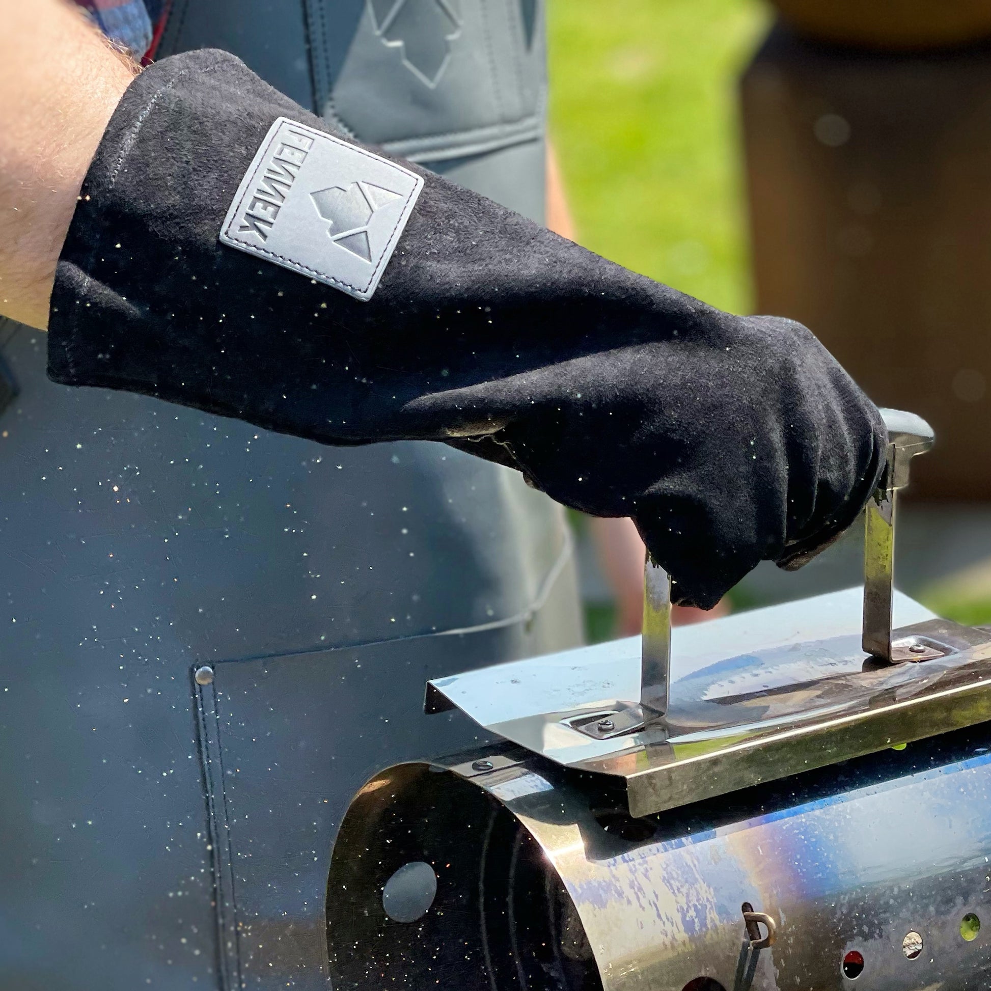 schwarzer Leder-Grillhandschuh im Einsatz, hält einen Kohlekamin