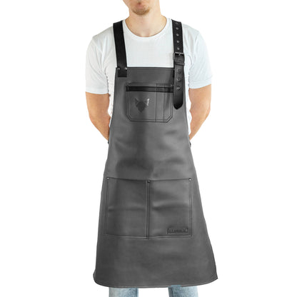 Brustbereich Leder-Grillschürze mit geprägtem FENNEK-Logo und mit verstellbarem Lederriemen, Schnalle und aufgesetzten Taschen, getragen von einem Mann