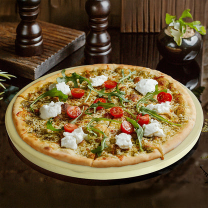 Pizzastein mit einer frisch gebackenen Pizza darauf die mit Käse, Rucolasalat und Tomaten belegt ist.