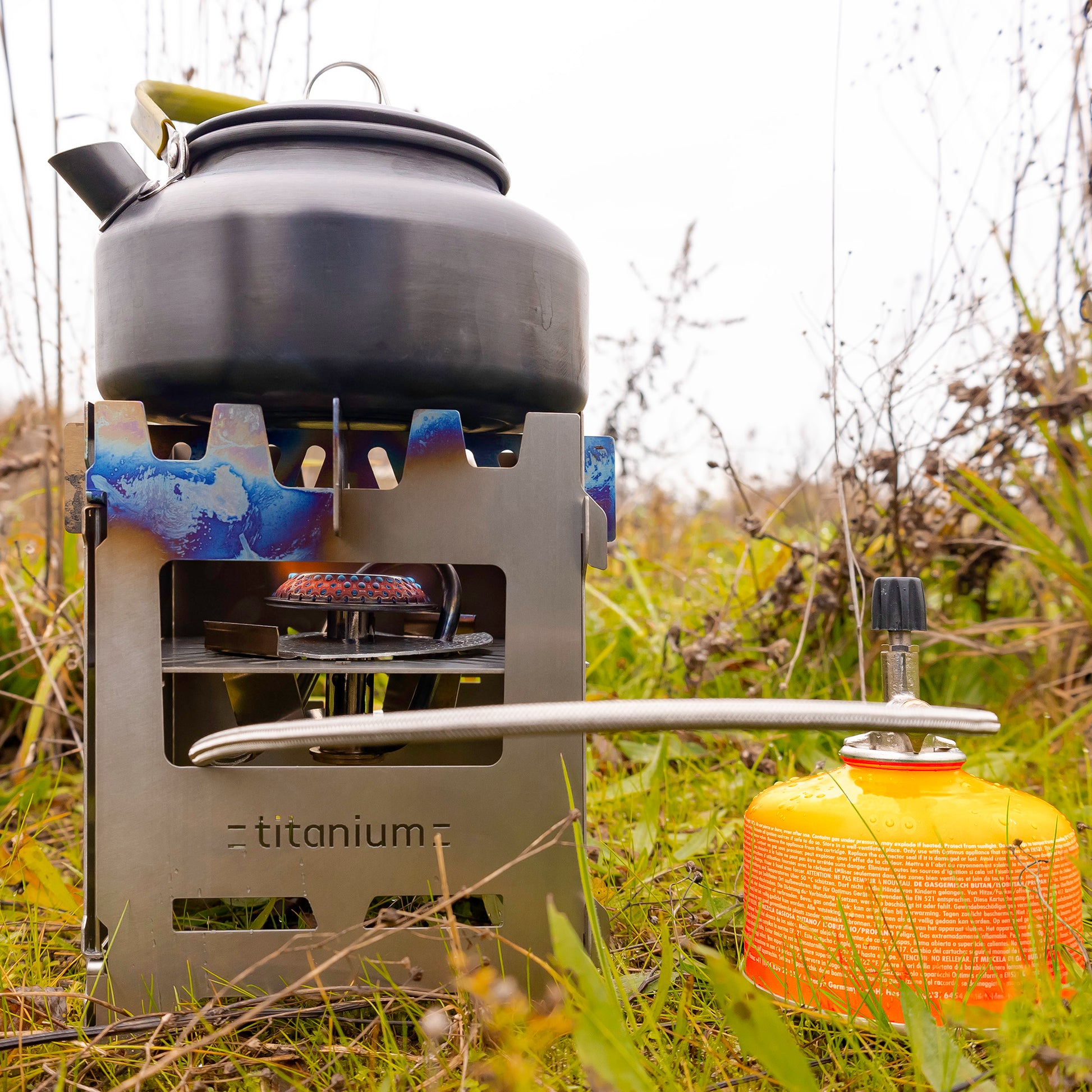 Blick auf einen Hobokocher aus Titan mit einem Wasserkessel darauf befeuert mit einem Gasbrenner der mittels Einsatz für Trangia Gaskocher in den Hobokocher verbaut wurde.