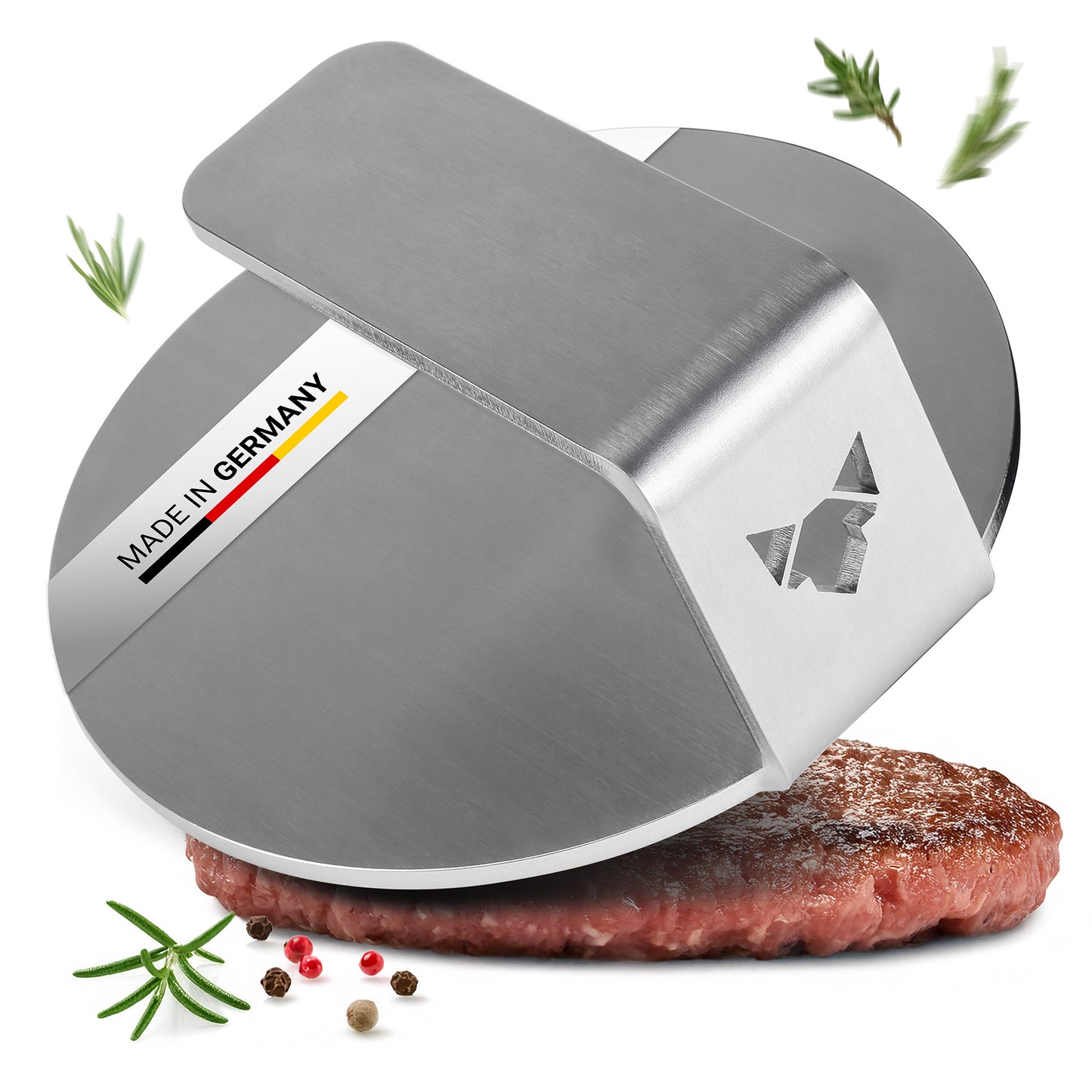 Der FENNEK Burger Smasher aus massiven 4,0 mm Edelstahl - Made in Germany vor weißem Hintergrund. Man sieht etwas Rosmarin neben dem Smasher, außerdem ist ein smashed Burger Pattie unter der Burger Presse zu sehen.