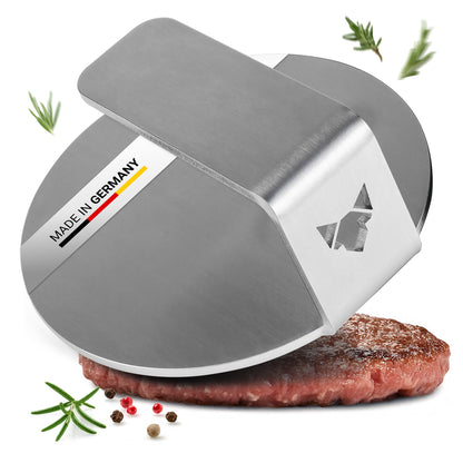 Der FENNEK Burger Smasher aus massiven 4,0 mm Edelstahl - Made in Germany vor weißem Hintergrund. Man sieht etwas Rosmarin neben dem Smasher, außerdem ist ein smashed Burger Pattie unter der Burger Presse zu sehen.