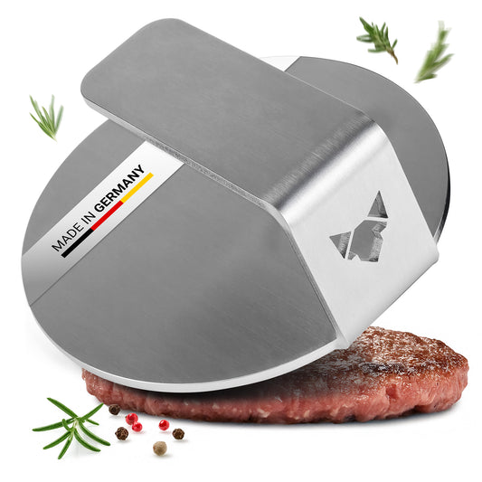 Der FENNEK Burger Smasher aus massiven 4,0 mm Edelstahl - Made in Germany vor weißem Hintergrund. Man sieht etwas Rosmarin neben dem Smasher, außerdem ist ein smashed Burger Pattie unter der Burger Presse zu sehen.