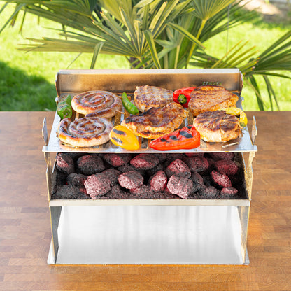 Der FENNEK 2.0 steht in einem Garten auf einem Tisch. Auf ihm brutzelt Fleisch und Gemüse.