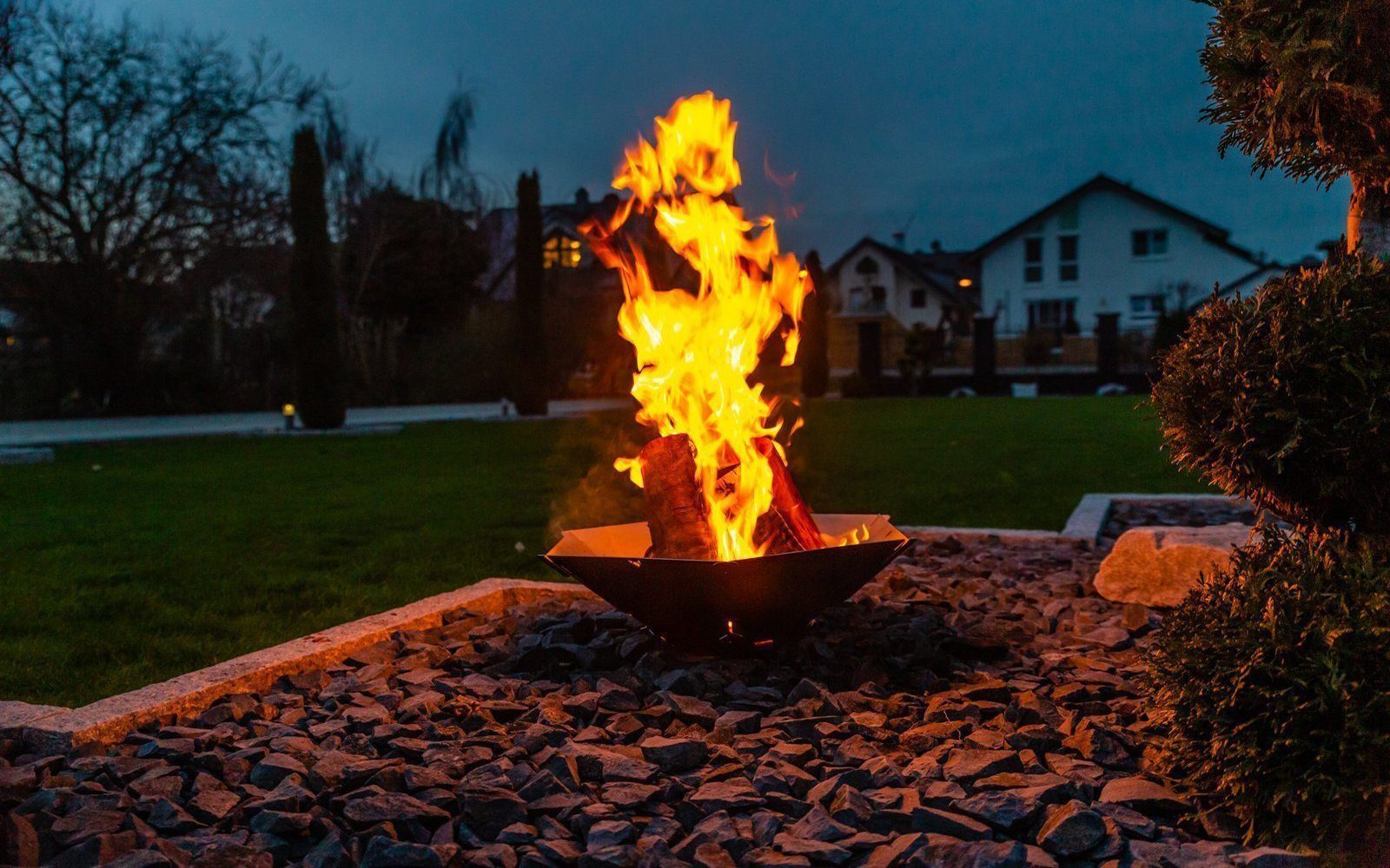 Brennendes Feuer in der Feuerschale Hexagon bei Dunkelheit im Garten..