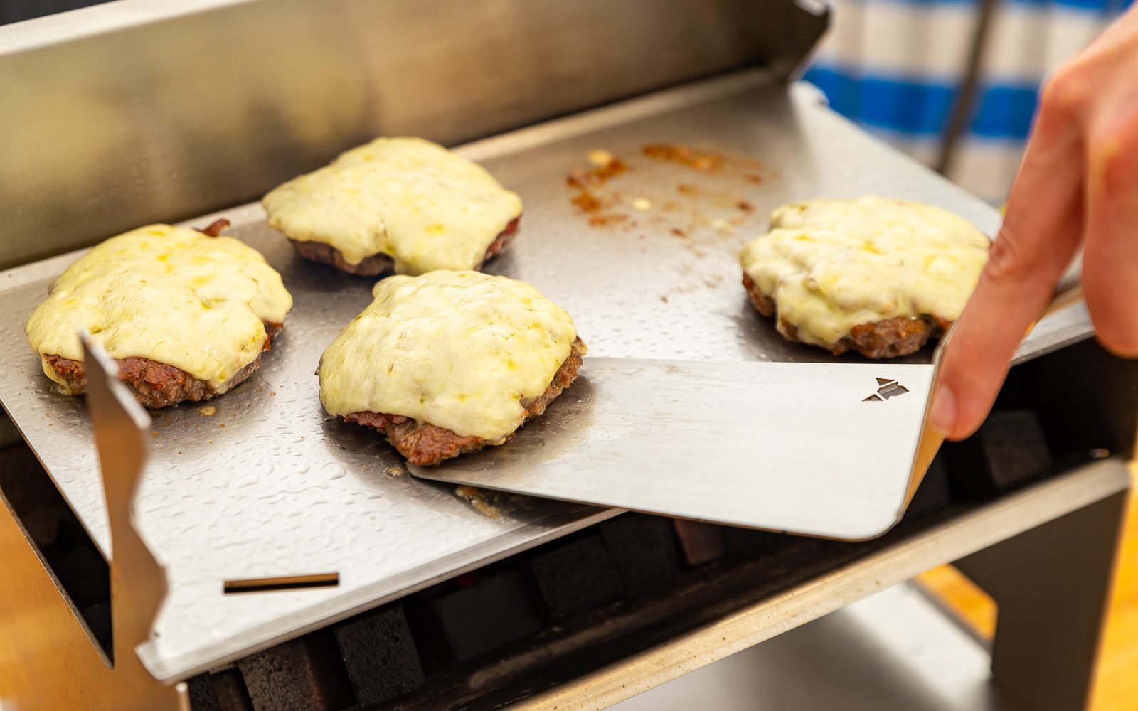 Edelstahl BBQ-Wender hebt mit Käse überbackene Burgerpatties von der Grillplatte